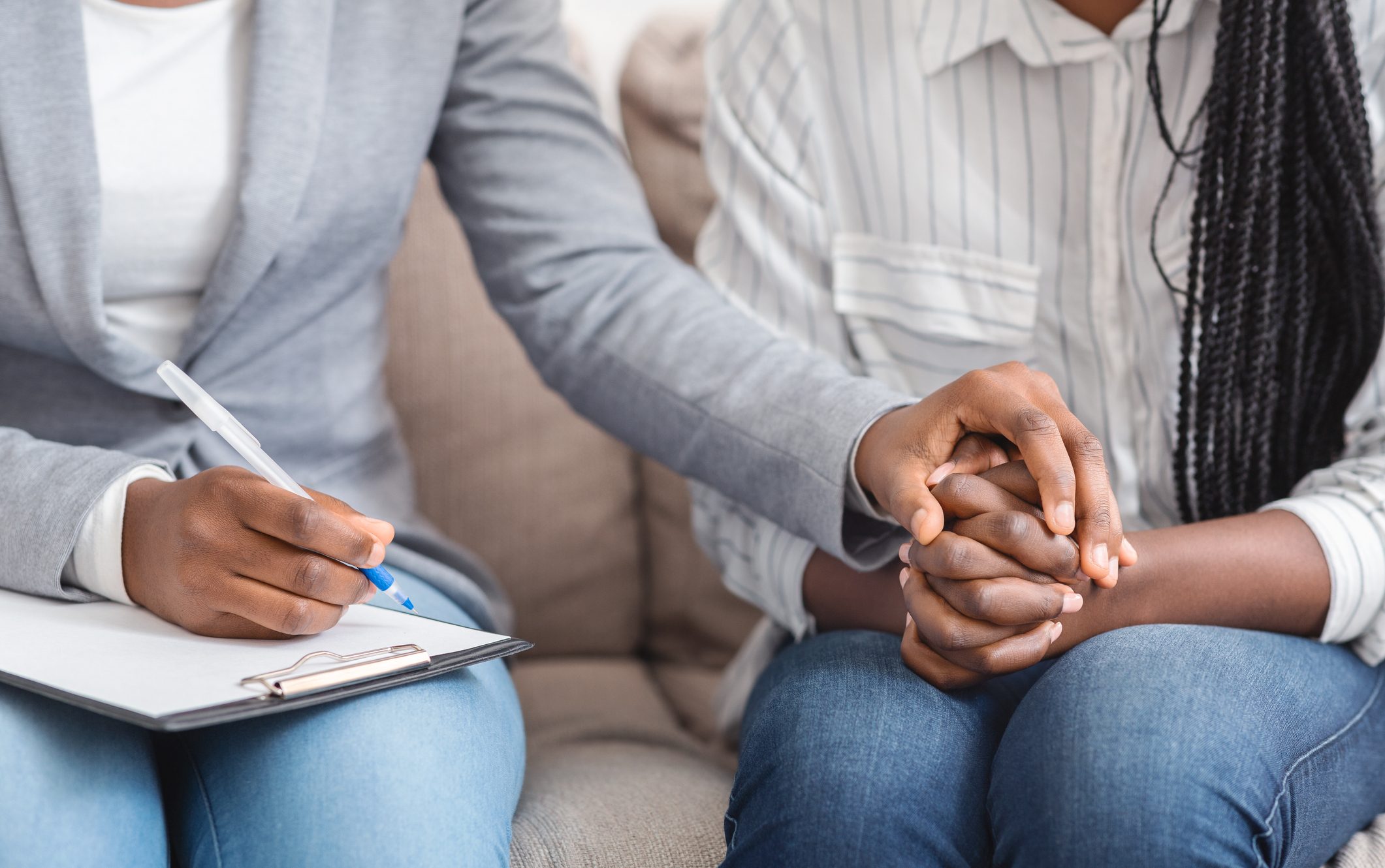 Professional support and help concept. Unrecognizable female councelor comforting her emotional patient and taking notes during therapy session.