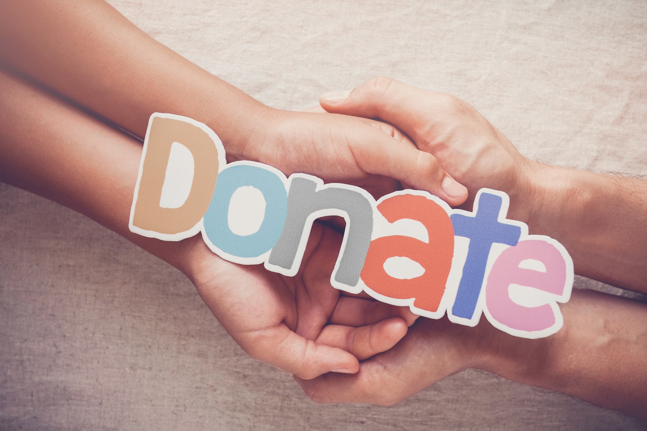 Adult and child hands holding word DONATE, donation and charity concept