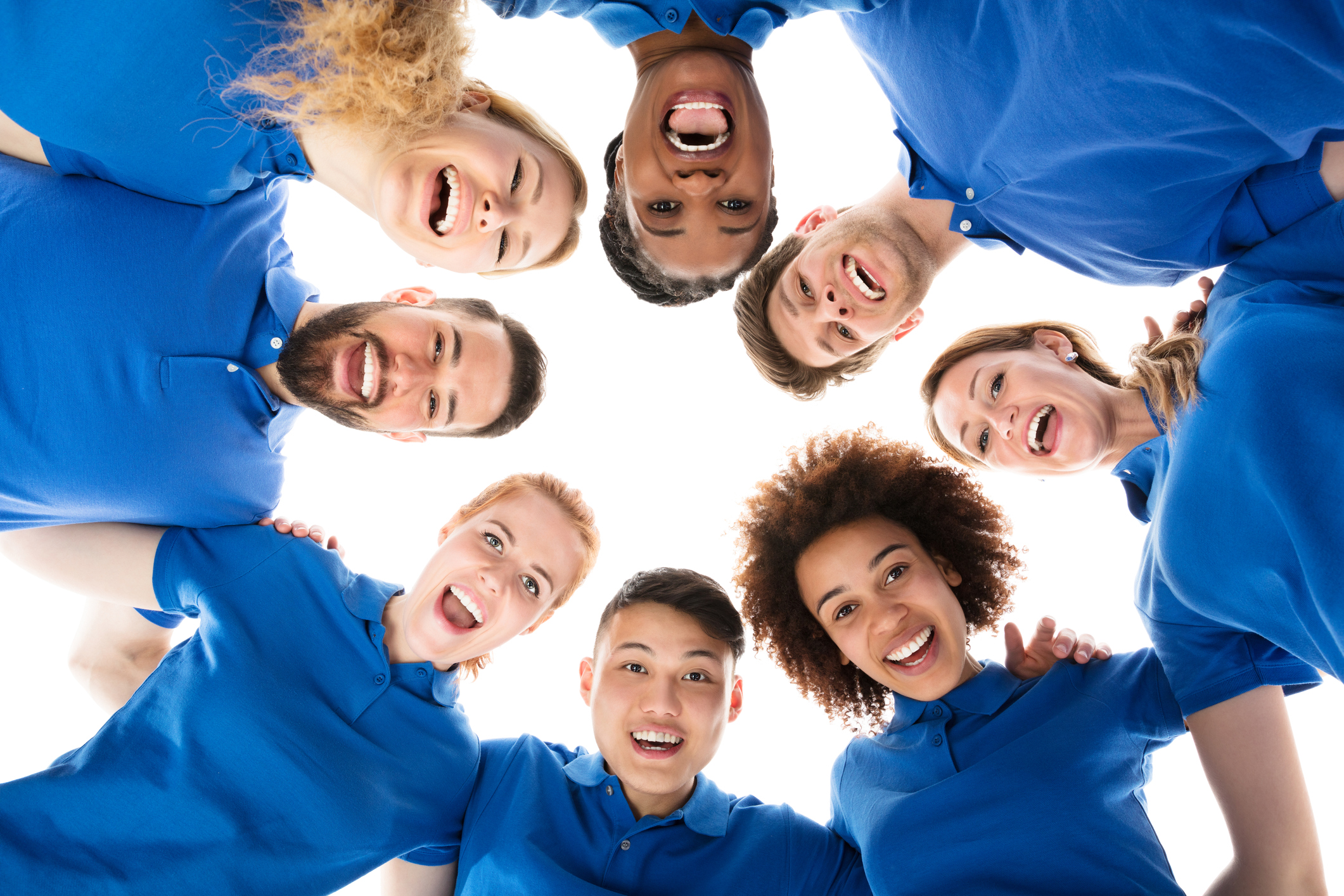 Group Of Smiling Janitors Forming Huddle Against White Background